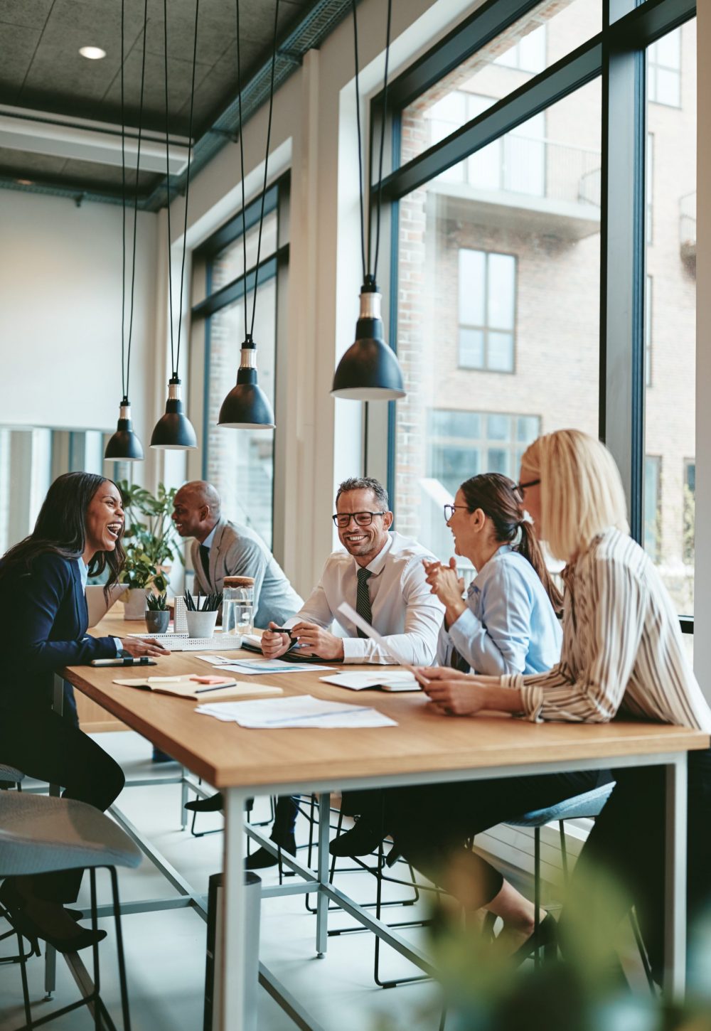 Smiling group of diverse businesspeople going over paperwork together during a meeting around a table in a modern office